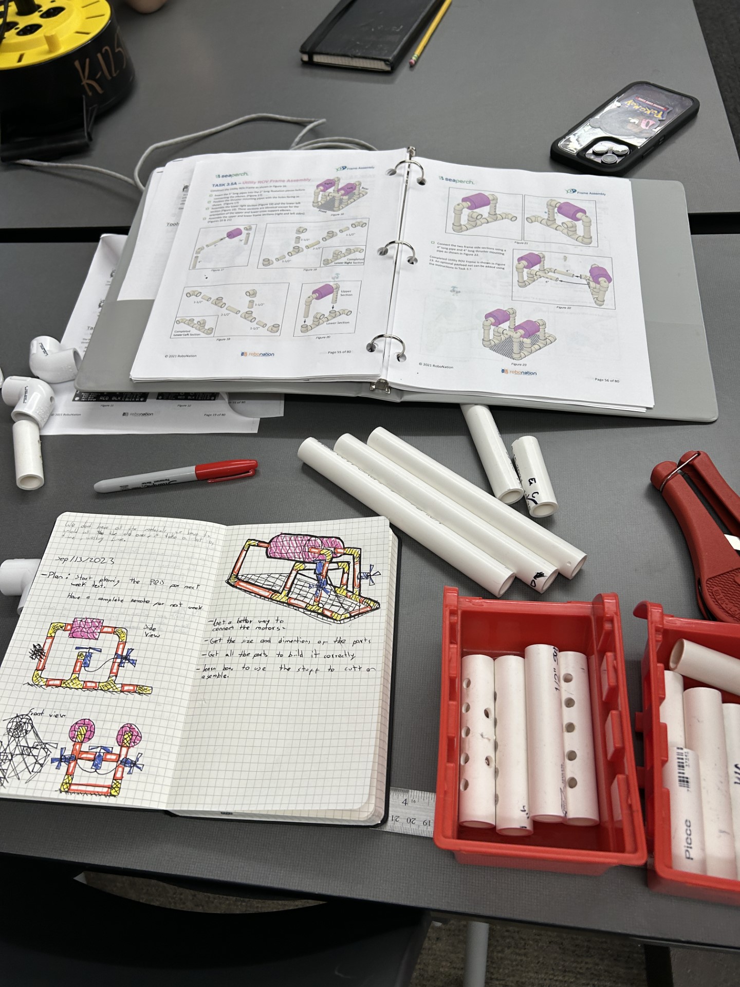 A table with a book and drawingsDescription automatically generated with medium confidence